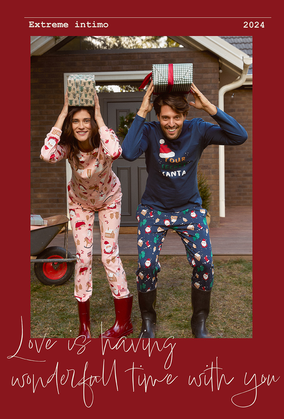 Muškarac i zena drže poklone iznad glave i nose novogodišnje pidžame