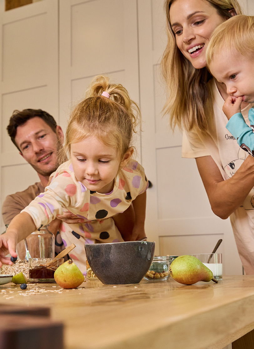 Porodica stoji oko stola u šarenim pidžamama