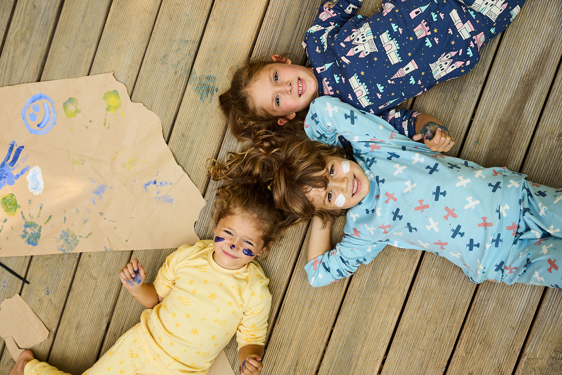 Dječak i dve djevojčice leže napolju u šarenim pidžamama na dug rukav