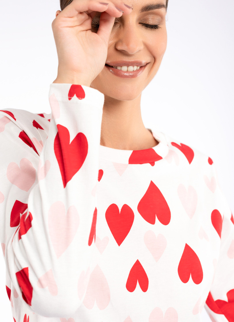 Žena stoji u bijeloj pidžami sa srcima na dug rukav