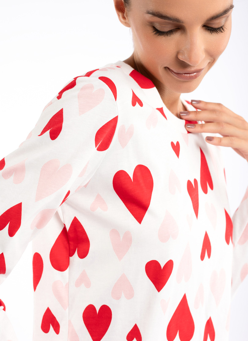 Žena stoji u bijeloj pidžami sa srcima na dug rukav 