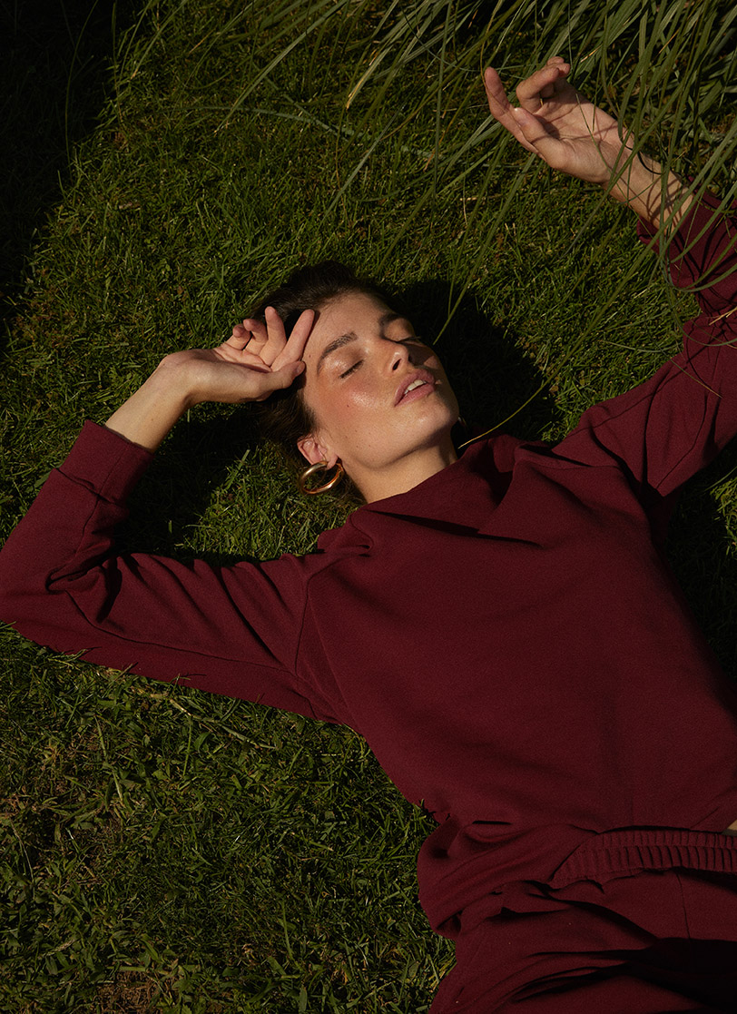 Djevojka leži na travi u bordo trenrci na dug rukav